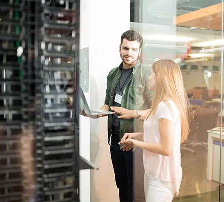 two business people standing server room with laptop discussing
